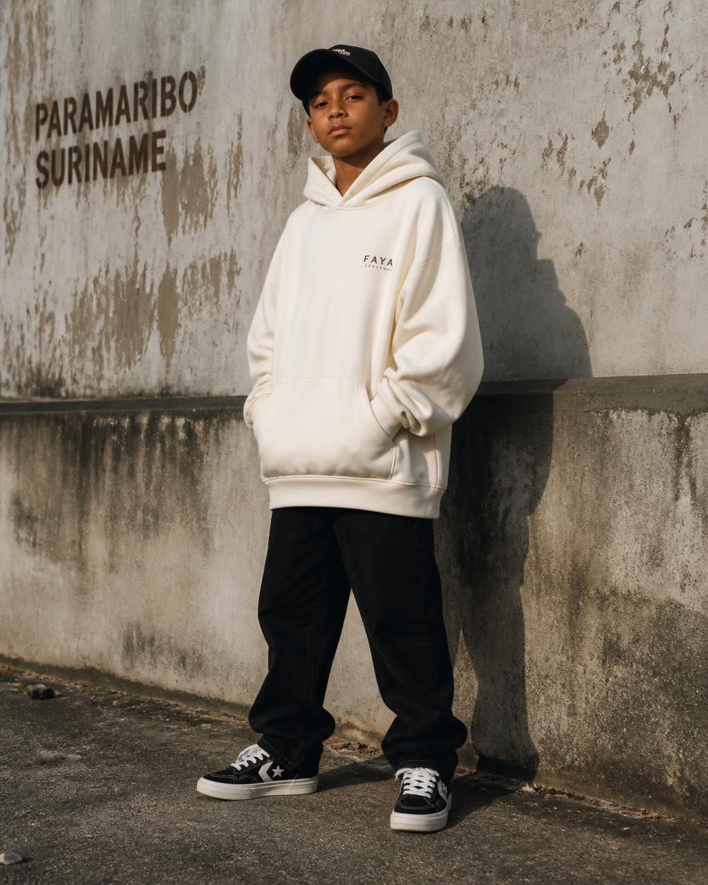 Young boy wearing an off-white FAKA hoodie against a concrete wall in Paramaribo